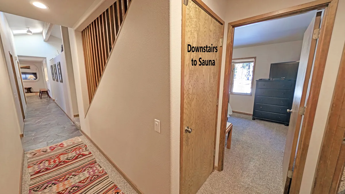 A bright interior hallway leading to a door marked 'Sauna' hints at both the wellness amenities inside and easy access between private and shared spaces. The decorative rug and natural light add warmth, while the visible sauna door directly connects to the relaxation options described in the section.