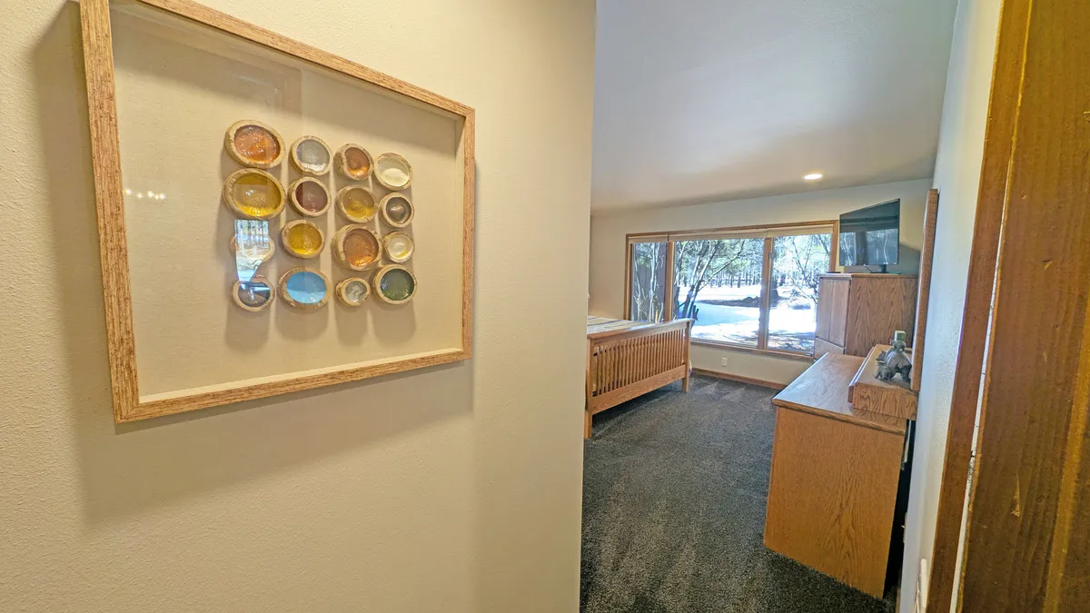 This image highlights a calm and inviting interior space with large windows that let in abundant natural light and offer views of the outdoors. The room features comfortable wooden furniture and a soothing atmosphere, suggesting it's a spot where guests and pets alike can rest while staying connected to the outdoors.